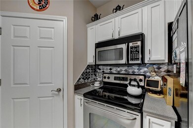 Kitchen with white cabinetry, appliances with stai