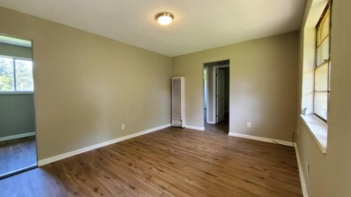 Unfurnished bedroom with dark wood-style floors and a heating unit