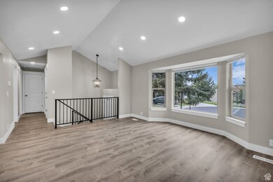 Spare room featuring light wood-style flooring, lofted ceiling, a chandelier, and recessed lighting