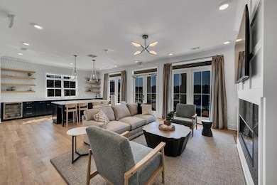 Living room with french doors, light hardwood / wood-style floors, and beverage cooler