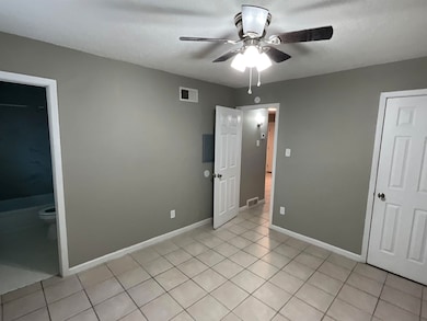 Unfurnished bedroom featuring ceiling fan, visible vents, baseboards, and light tile patterned flooring