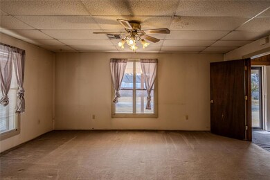 Carpeted empty room featuring a paneled ceiling and a ceiling fan