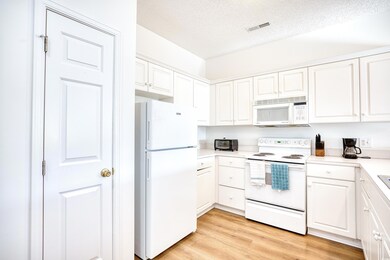 Kitchen with a textured ceiling, white cabinets, l