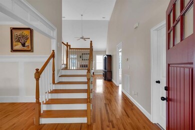 Entrance foyer with light wood-style flooring, ceiling fan, stairs, and a towering ceiling