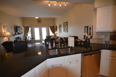 Kitchen with open floor plan, french doors, dishwasher, white cabinets, and tasteful backsplash