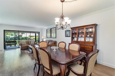 Dining room with hardwood / Tile wood-like flooring, ornamental molding, and an inviting chandelier