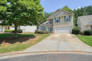 Traditional-style home featuring a garage, driveway, and a front lawn