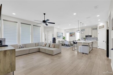 Living area with light wood-style floors, recessed lighting, ceiling fan, and a chandelier