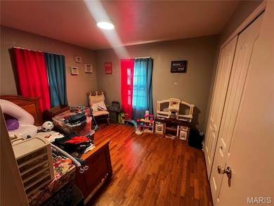 Bedroom with wood finished floors and a closet