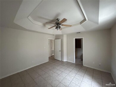 Unfurnished bedroom with a tray ceiling, light tile patterned flooring, and ensuite bath