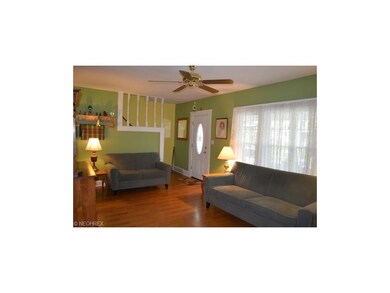 Spacious living room with refinished wood floors, ceiling fan, replacement windows and newer front door.