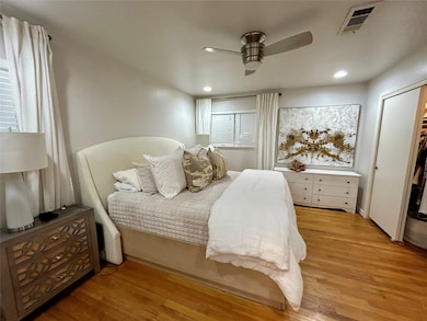 Primary bedroom with wood floors and ceiling fans.