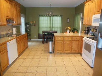Lots of cabinets in the kitchen, tile floors looking toward the nook area, door leading out onto the deck.