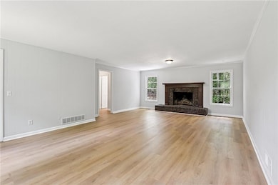 Unfurnished living room with light wood-style floors, a fireplace, and baseboards