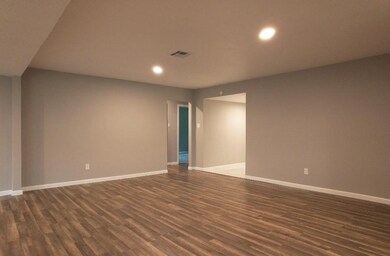 This interior space features warm wood flooring and a door, creating an inviting atmosphere. With quality laminate or hardwood floors, plus well-finished walls and ceiling, it’s a versatile area that adds charm to any property.
