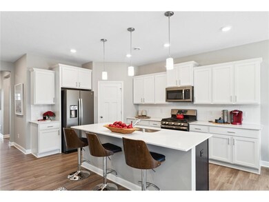 One-level living with dream kitchen featuring an oversized island, quartz countertops, tile backsplash, slate finish appliance package including refrigerator and walk-in pantry. Photo of model home, colors and finishes will vary.