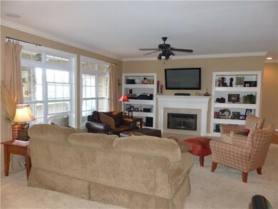 The living room has a gas log fireplace, built in shelves, a ceiling fan, and surround sound. 