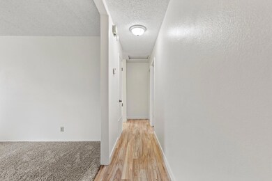 Looking down hallway to bedrooms. Room with carpet on the left is open to possibilities of use.