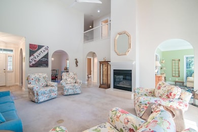 Living room featuring crown molding, light carpet, a fireplace, and a towering ceiling