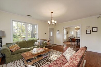 Living room with dark wood-style flooring, crown molding, and a chandelier