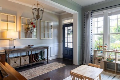 Foyer entrance featuring ornamental molding, a chandelier, a wainscoted wall, and wood finished floors