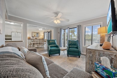 Carpeted living room with crown molding, ceiling fan, and a textured ceiling