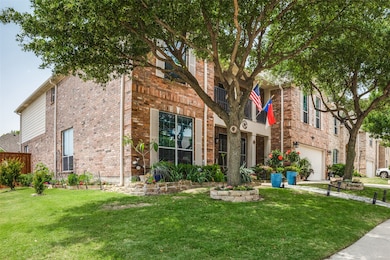 View of front of house with a front yard, brick siding, and a garage
