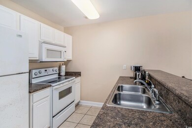 Kitchen with white appliances, a sink, dark counte