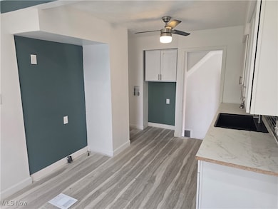 Kitchen featuring white cabinets, light countertops, light wood finished floors, and a ceiling fan