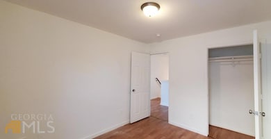 Unfurnished bedroom featuring wood finished floors, a closet, and baseboards
