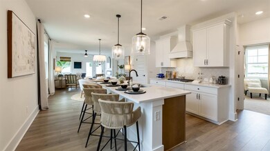 Kitchen featuring premium range hood, a sink, wood finished floors, open floor plan, and an island with sink
