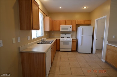 Kitchen featuring white appliances, light countertops, and light tile patterned flooring