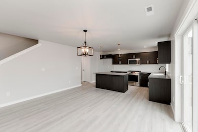 Kitchen featuring a center island, hanging light fixtures, appliances with stainless steel finishes, light wood-type flooring, and a chandelier
