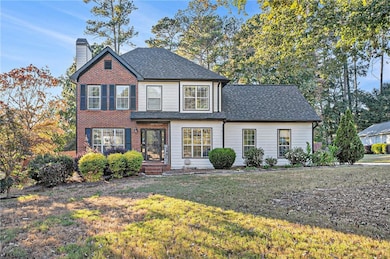 Traditional home with a chimney, a front lawn, and a shingled roof