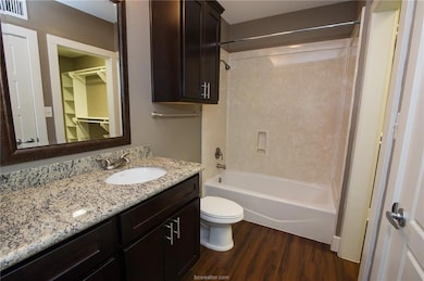 Bathroom with toilet, wood finished floors, bathtu