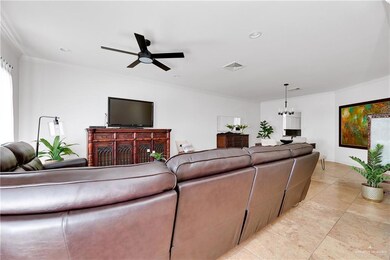 Living room with a fireplace, ceiling fan with notable chandelier, and crown molding