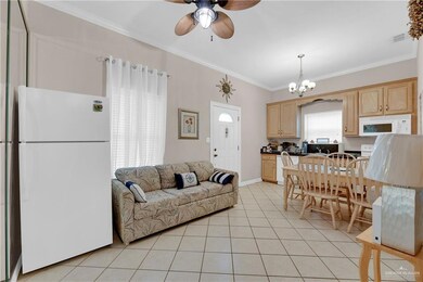 Living room with ceiling fan with notable chandelier, ornamental molding, and light tile patterned floors