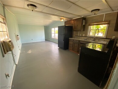 Kitchen with black refrigerator, stove, lofted ceiling, and sink