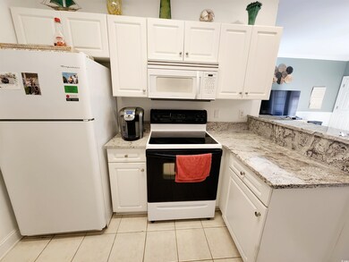 Kitchen featuring white cabinetry, light stone cou