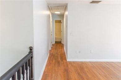 Corridor featuring wood finished floors, attic acc