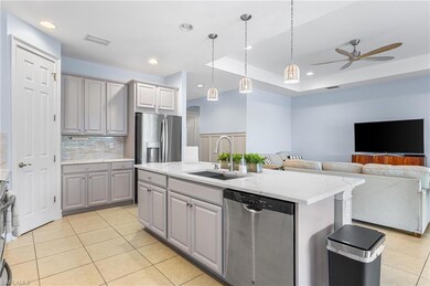 Kitchen featuring stainless steel appliances, a sink, gray cabinetry, light tile patterned flooring, and ceiling fan