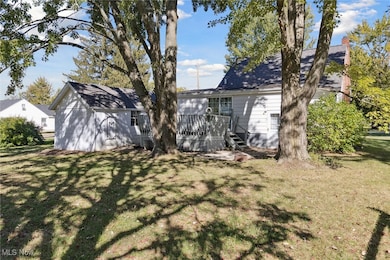Back of house with a lawn, a wooden deck, and a shingled roof