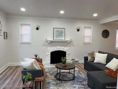 Living room featuring wood finished floors, ornamental molding, a fireplace with flush hearth, and recessed lighting