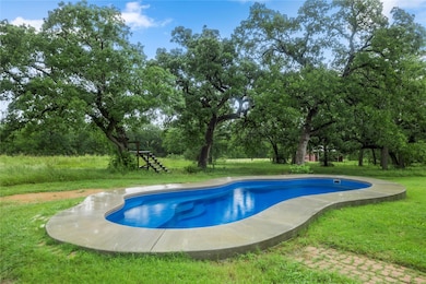 Outdoor pool with view of scattered trees and a l