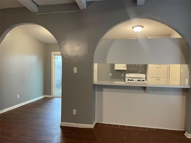 Kitchen featuring a textured ceiling, light countertops, white gas stove, a breakfast bar area, and dark wood-type flooring