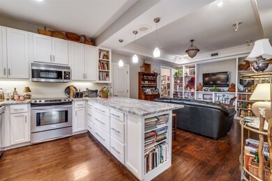 Kitchen with decorative light fixtures, open shelves, white cabinetry, light stone countertops, and stainless steel appliances