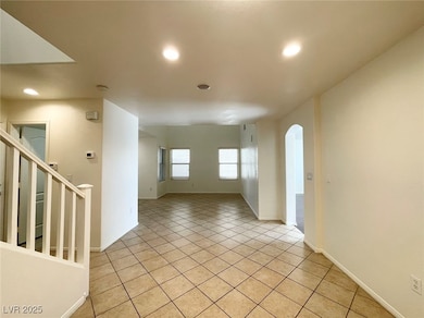 Unfurnished room with light tile patterned floors, arched walkways, stairway, and recessed lighting