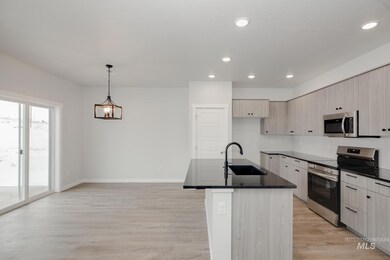 Kitchen featuring stainless steel appliances, modern cabinets, an island with sink, decorative backsplash, and light wood-style flooring