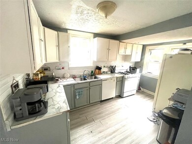Kitchen with light countertops, light wood-style floors, white appliances, a textured ceiling, and decorative backsplash