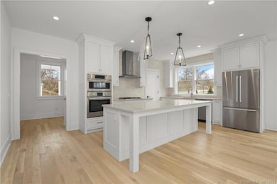 SS hood over 5-burner Bosch gas cooktop. Inset, custom white cabinetry. Recessed lighting. Cased opening to foyer, entry to mudroom/drop zone, and privacy door to first floor bedroom/office.